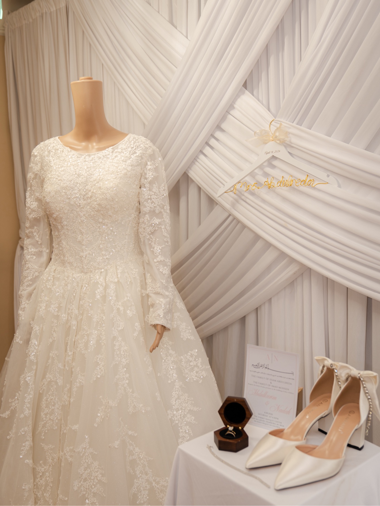 Nadah's wedding dress, shoes, rings, and invitation arranged together