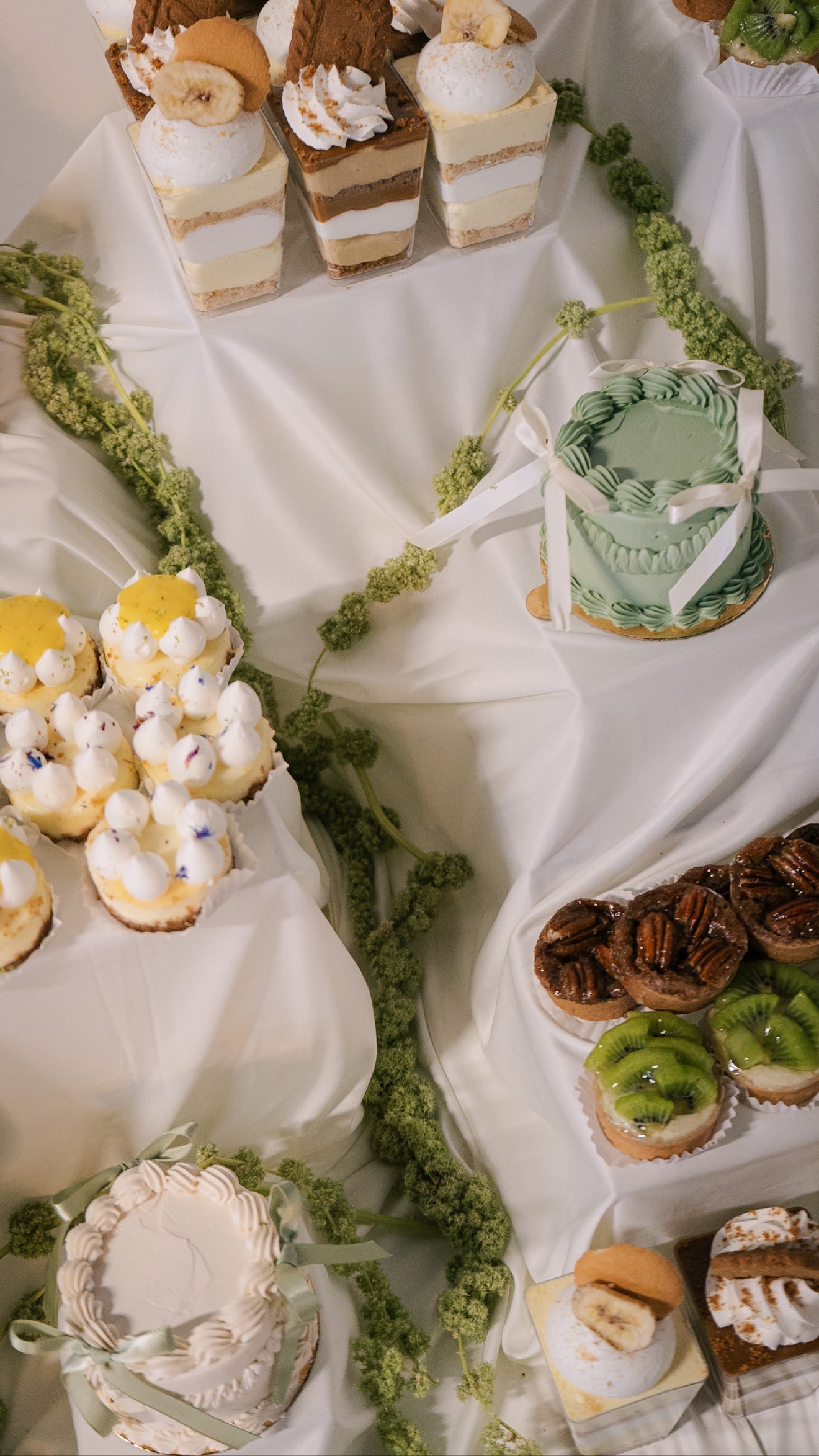 Assorted cakes and desserts arranged with greenery