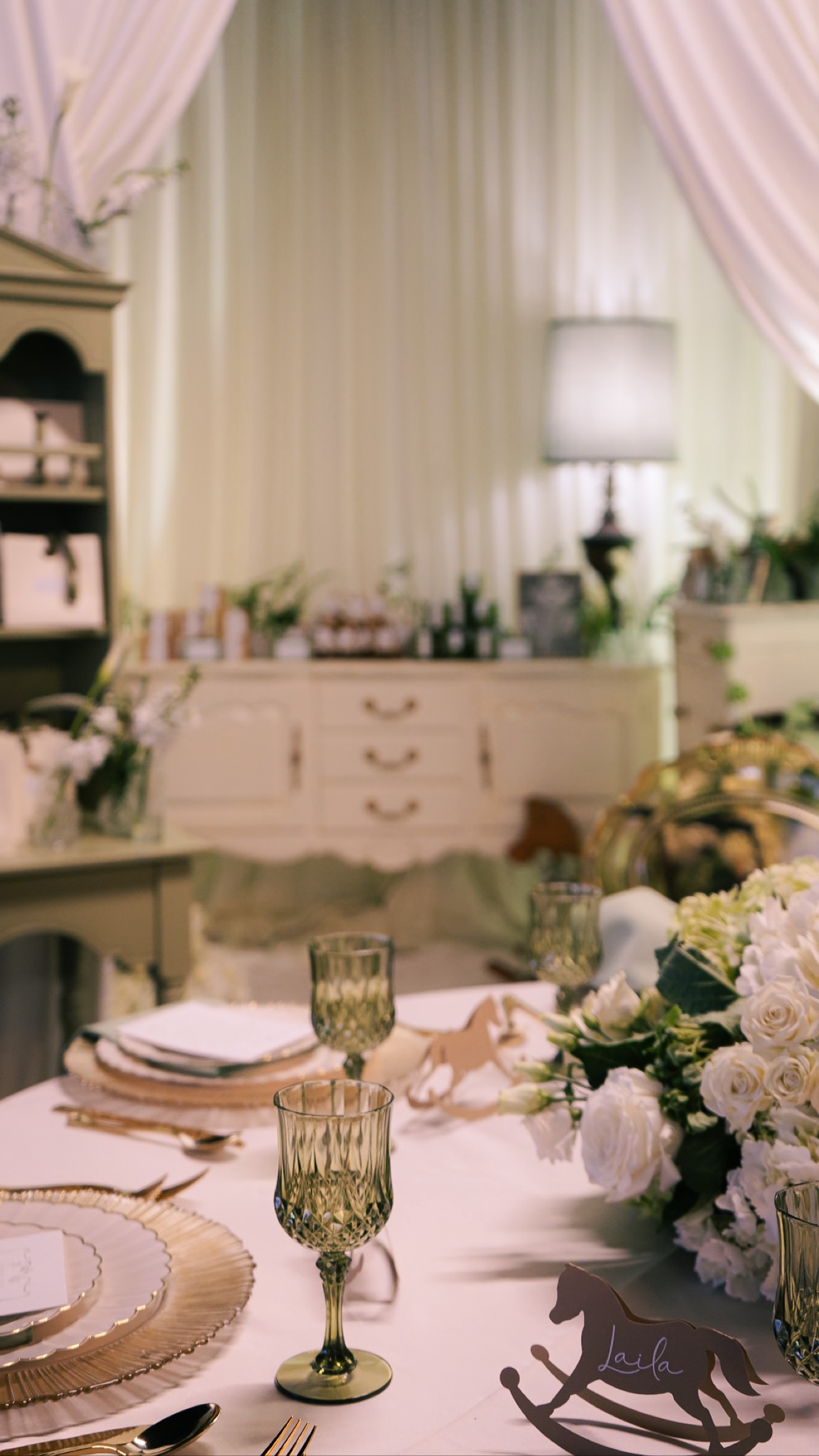 Reception table with flowers, green glassware, and rocking-horse place cards